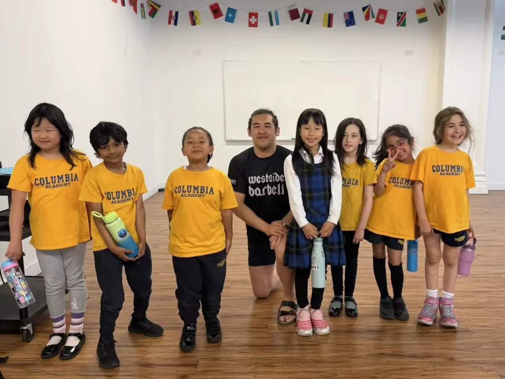 Columbia Academy Elementary School students standing under a row of flags from around the world